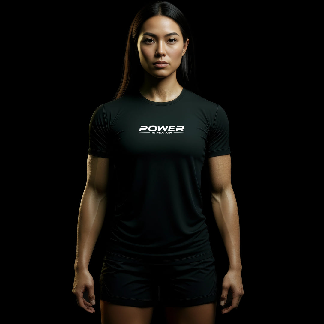 MAXPULSE™ LITE Women | POWER IN MOTION | BlackPulse™ performance tee | Front model view showing lightweight breathable fit with clean white chest print | Female fitness model front-facing with strong posture in minimal dark studio setting | Featured in MAXPULSE™ LITE Women Tee