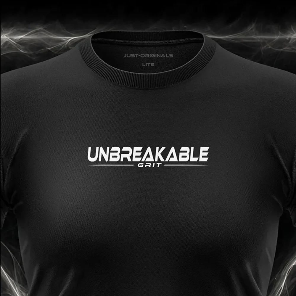 Close-up of the JUST-ORIGINALS™ MAXPULSE™ LITE Women UNBREAKABLE GRIT design on a BlackPulse™ performance t-shirt, featuring white and silver UNBREAKABLE typography, white GRIT text, white accent line, silver premium neck label, and premium athletic fabric.