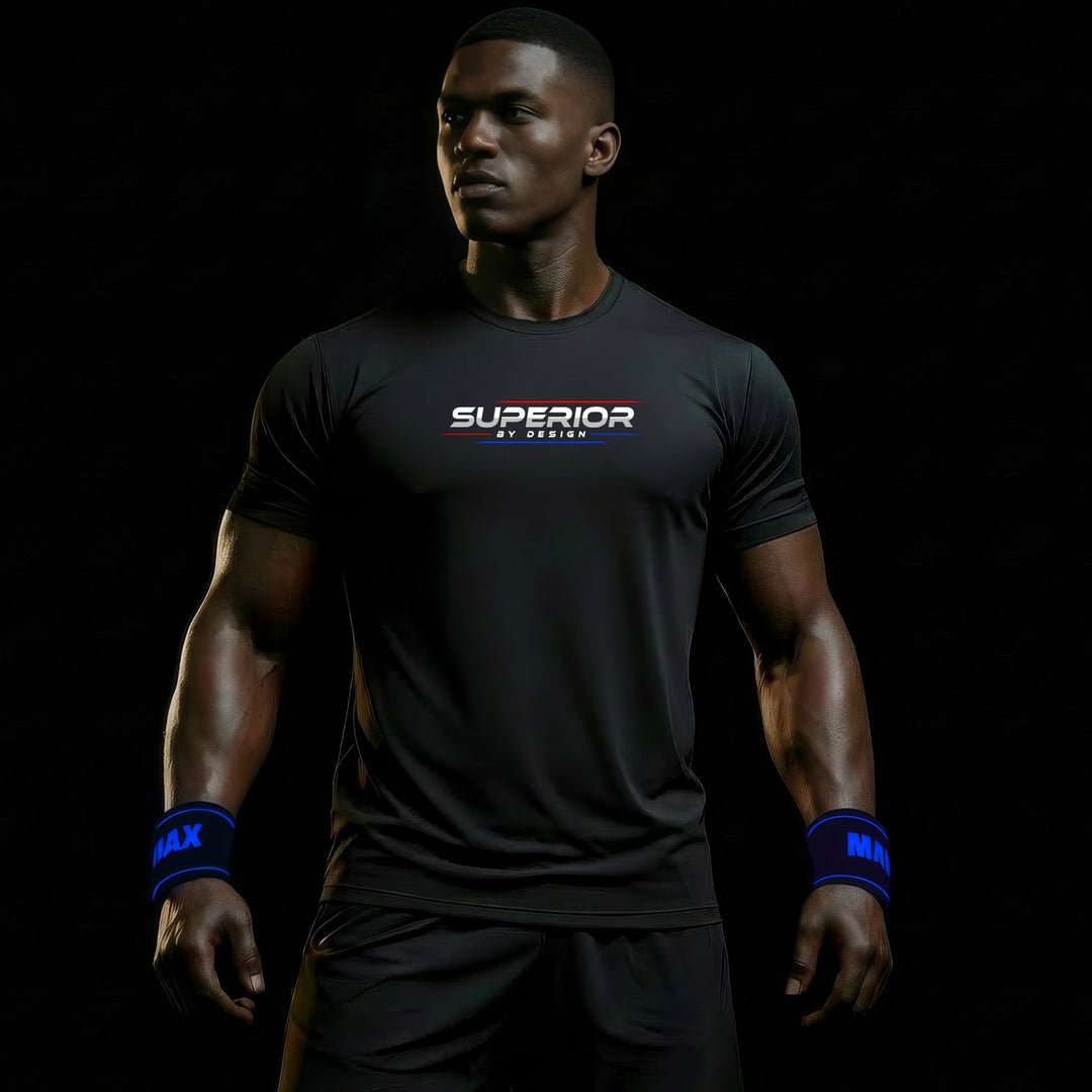 MAXPULSE™ PRO | SUPERIOR BY DESIGN | Men Performance Tee | BlackPulse™ premium black athletic shirt with SUPERIOR BY DESIGN chest print and blue accent underline | Male fitness model looking to the side with strong posture and defined physique in dark studio lighting | Featured in MAXPULSE™ PRO Men Tee