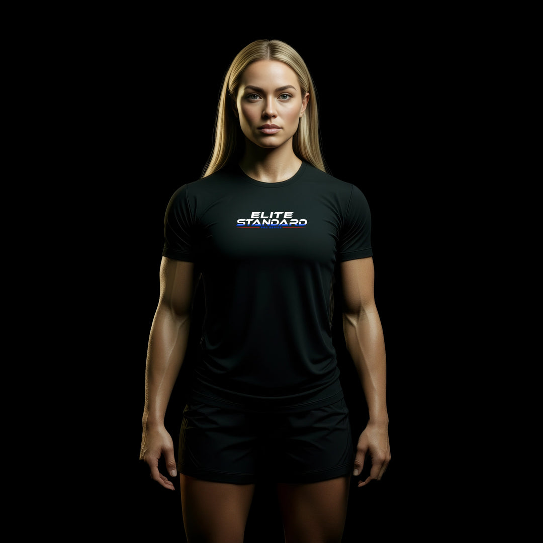 MAXPULSE™ Women | Elite Standard Performance Tee | Athletic female fitness model wearing black MAXPULSE™ training shirt with ELITE STANDARD chest print on a dark studio background | JUST-ORIGINALS™